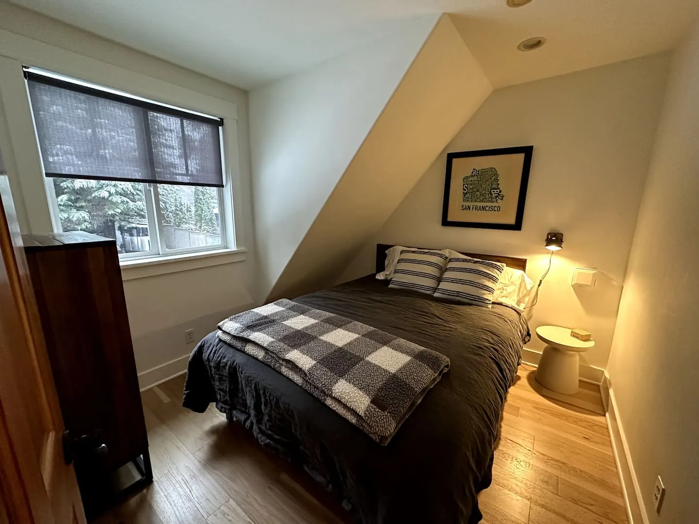Cozy bedroom with a double bed and plaid bedding under a sloped ceiling