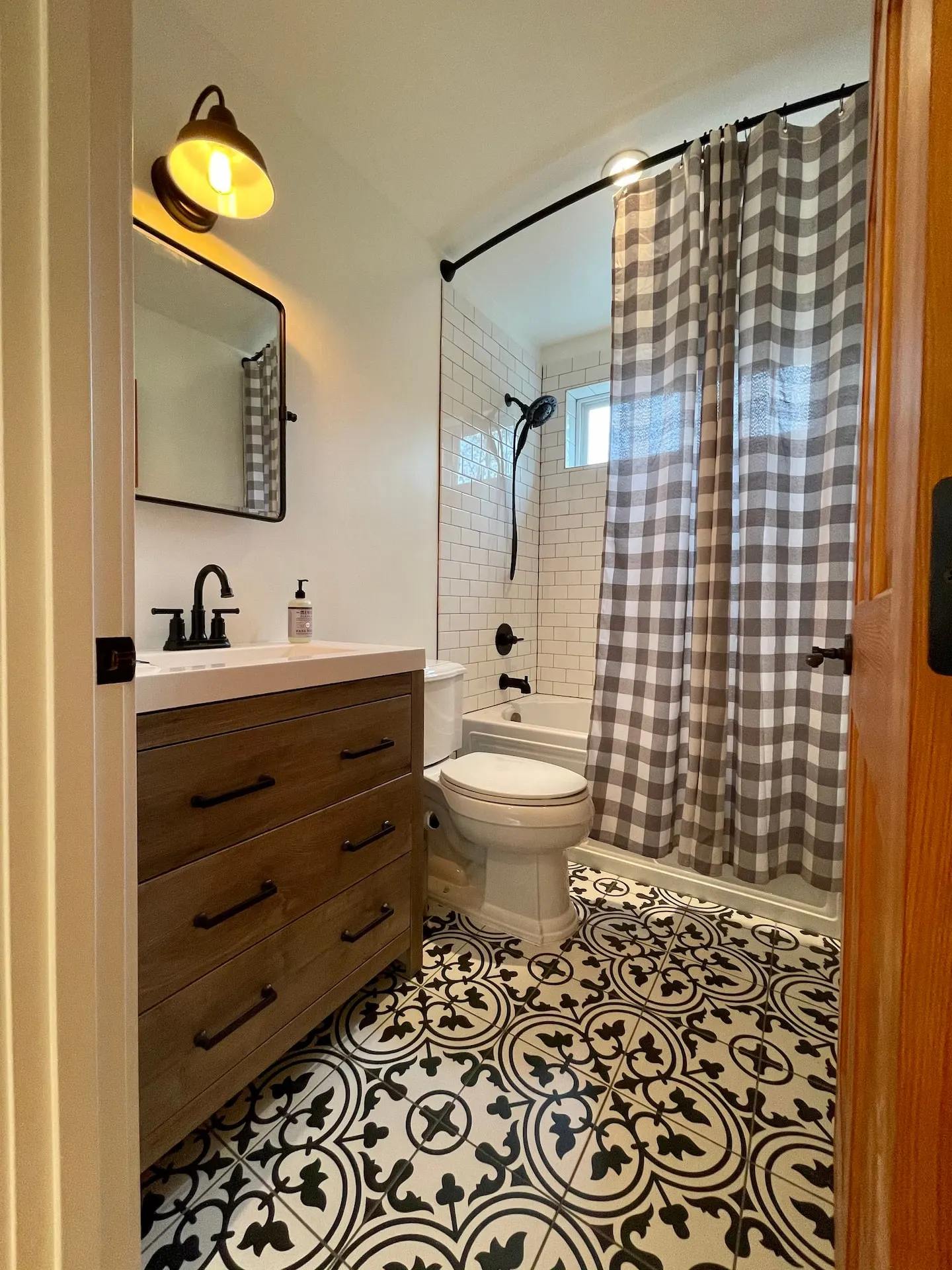 Bathroom with wood vanity, patterned tile floor and tub-shower