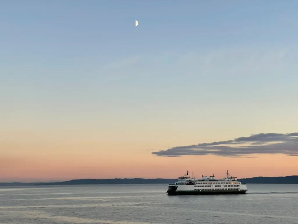 A Washington State ferry crossing Puget Sound at dusk under a half moon
